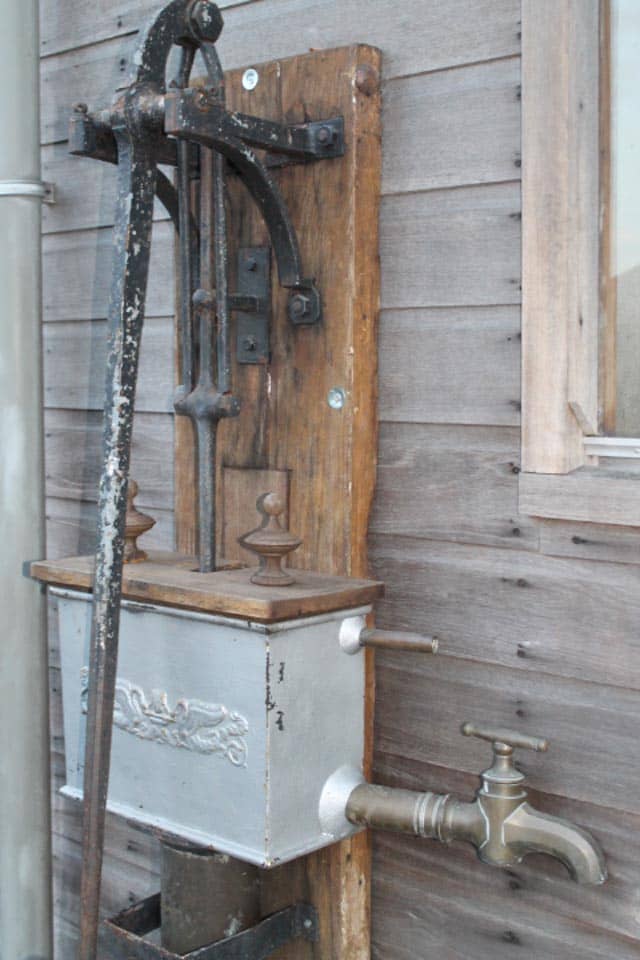Zeer-mooie-unieke-waterpomp-met-mooie-bak-op-bord.-staat-bij-oude-zagerij